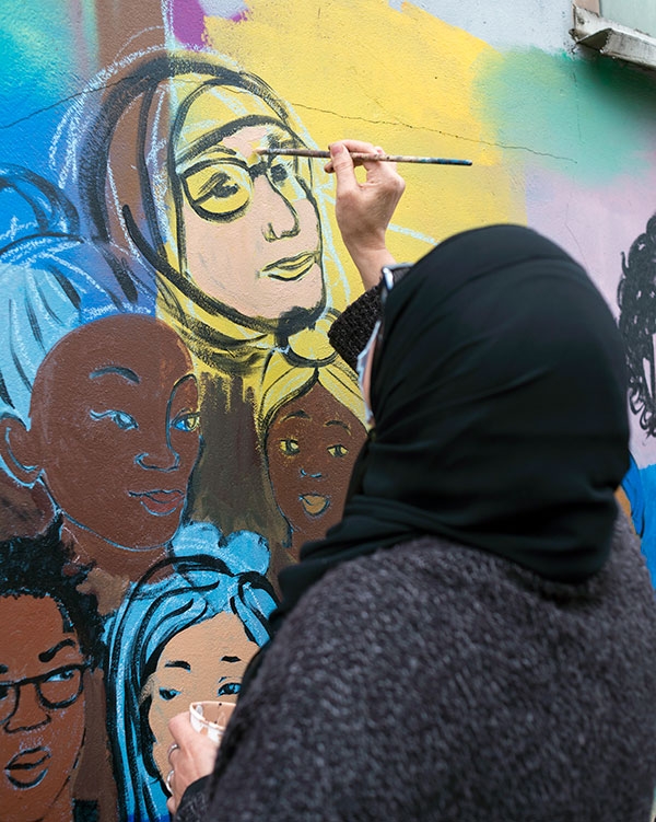 Aïcha met son visage en couleur, comme une trentaine d’autres habitants, dont les portraits s’unissent pour former un poing levé.