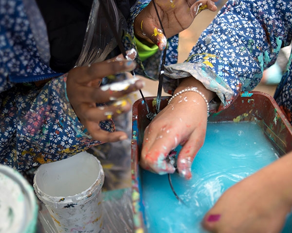 Les enfants nettoient leur matériel de peinture.
