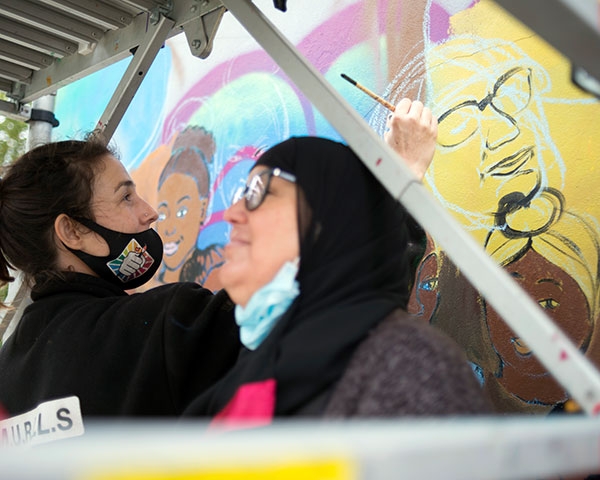 Nawak dessine les contours du portrait d’une habitante. Aïcha mettra ensuite elle-même son visage en couleur, comme une trentaine d’autres habitants, dont les portraits s’unissent pour former un poing levé.
